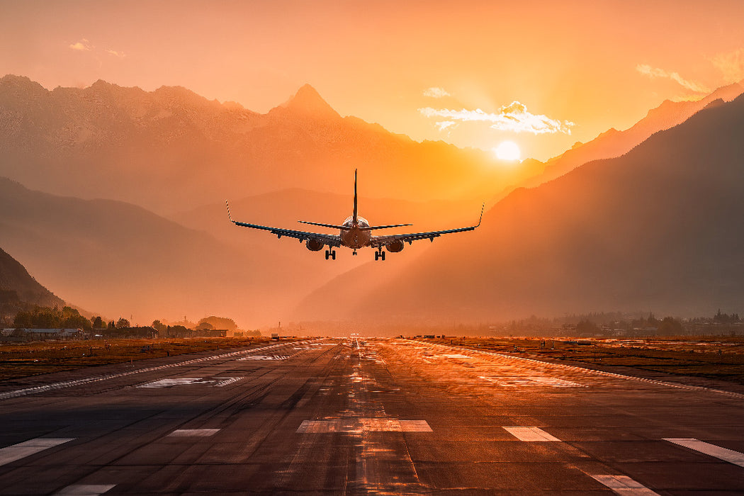 Premium Textil-Leinwand Flugzeug bei Landung im Sonnenuntergang vor Bergkulisse