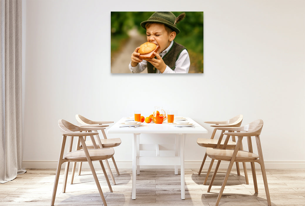 Premium Textil-Leinwand Kind in Tracht beißt in eine Leberkässemmel