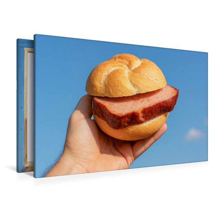 Premium Textil-Leinwand Hand hält Leberkässemmel vor blauem Himmel