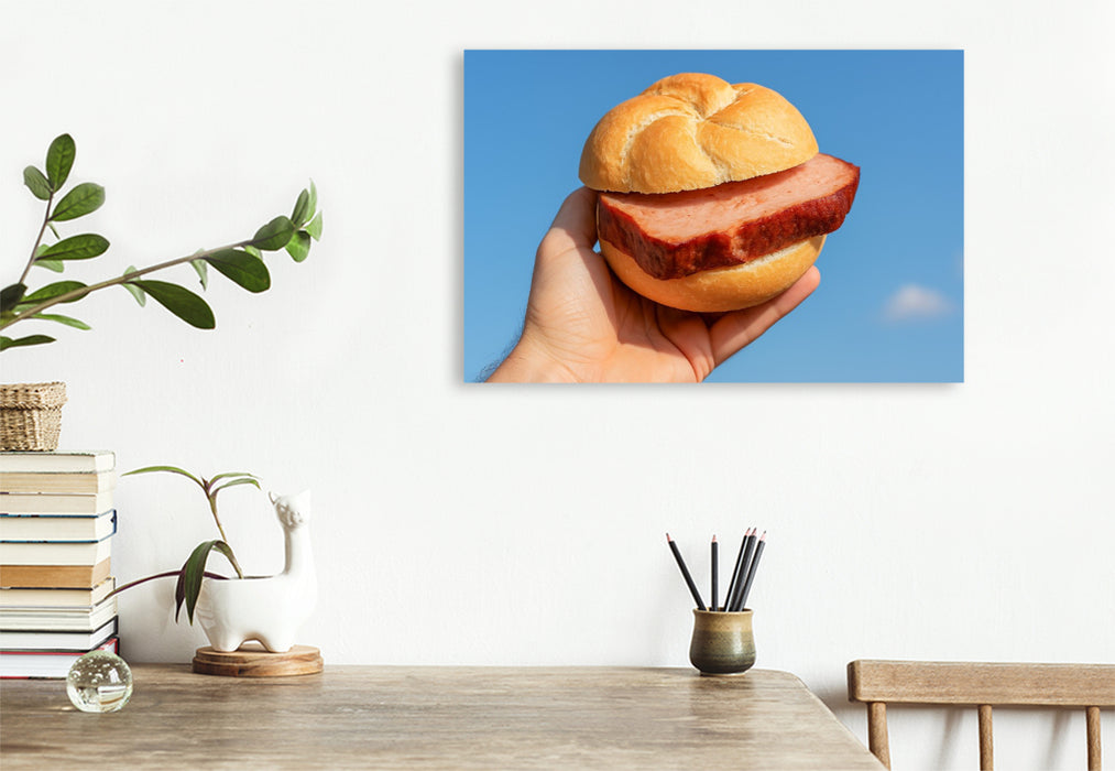 Premium Textil-Leinwand Hand hält Leberkässemmel vor blauem Himmel