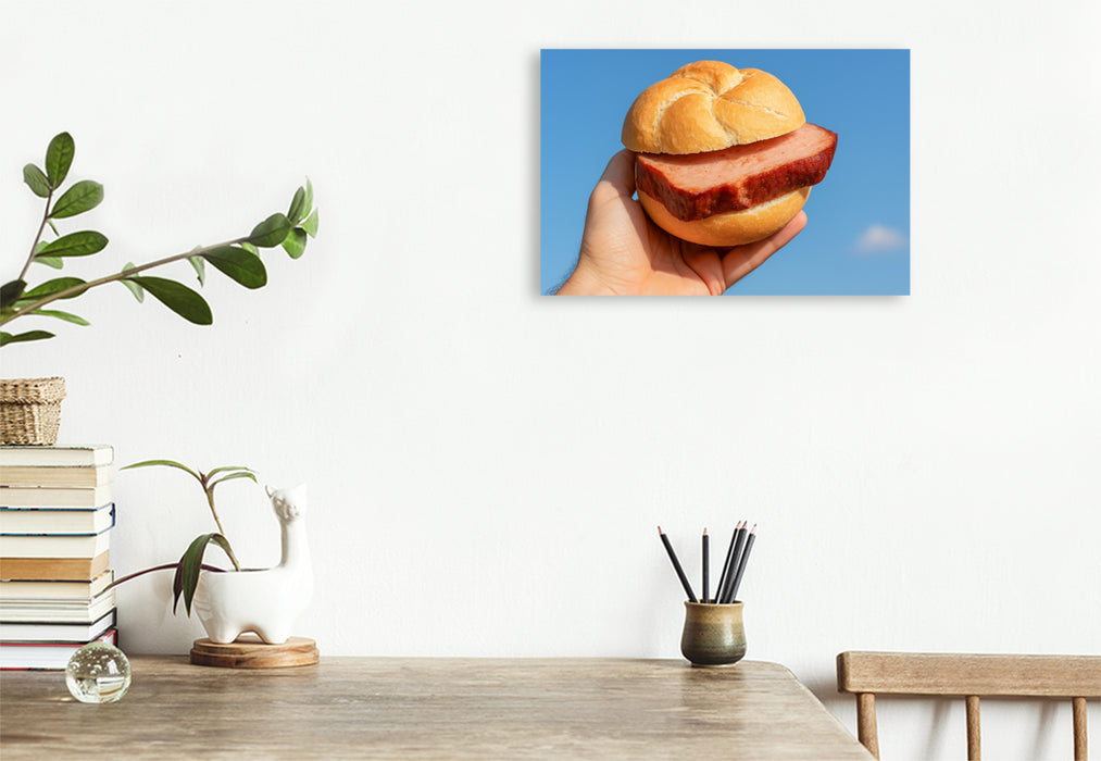 Premium Textil-Leinwand Hand hält Leberkässemmel vor blauem Himmel