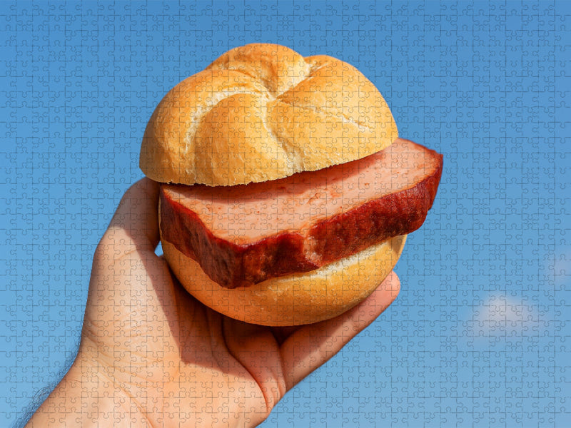 Hand hält Leberkässemmel vor blauem Himmel - CALVENDO Foto-Puzzle'