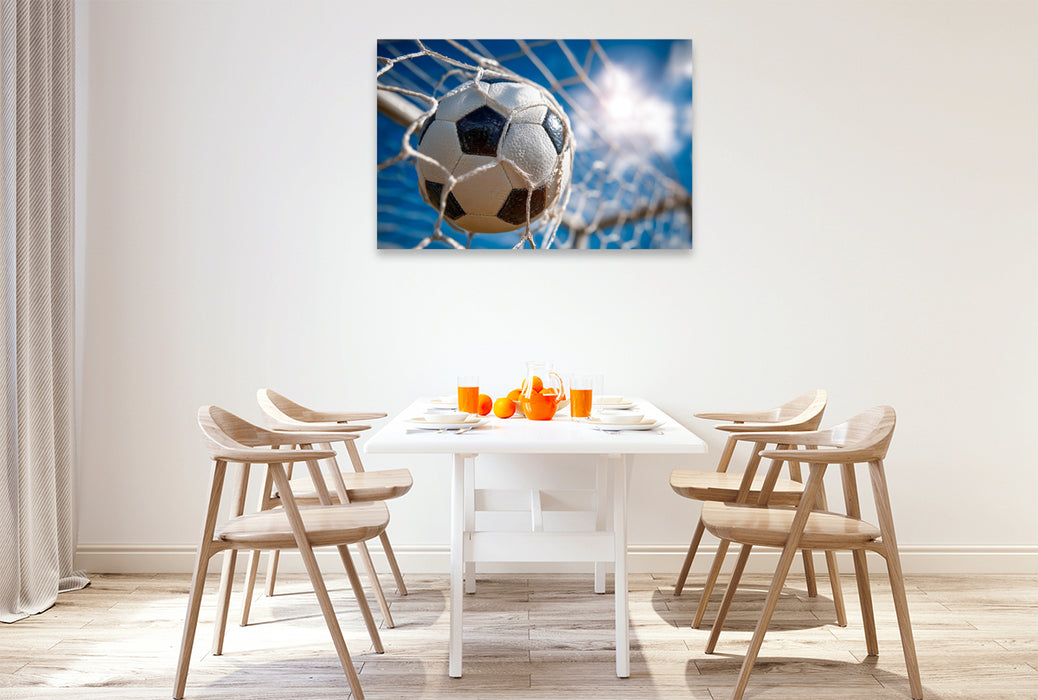 Premium Textil-Leinwand Ein Fußball schlägt kraftvoll im Tornetz ein und fängt den Moment des Erfolgs im perfekten Augenblick ein.
