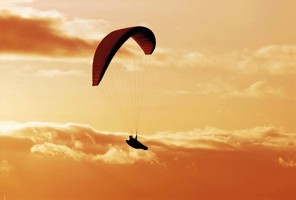 Premium Textil-Leinwand Premium Textil-Leinwand 120 cm x 80 cm quer Paragliding im warmen Licht der untergehenden Sonne.