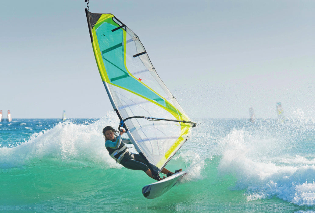 Premium Textil-Leinwand Premium Textil-Leinwand 120 cm x 80 cm quer Sportliche junge Windsurferin in der schäumenden Welle.